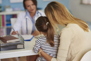 Foto di una mamma con la propria figlia in visita nello studio della pediatra