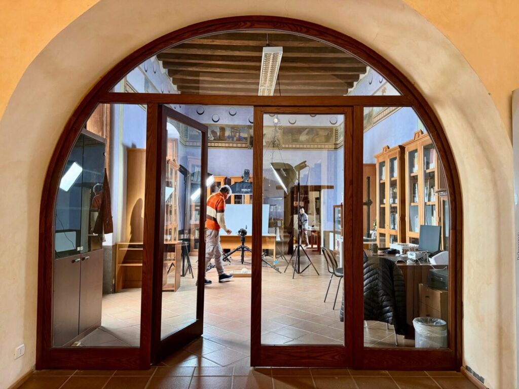 Porta di vetro aperta con vista sulla sala del cantiere di digitalizzazione del Museo Lametino