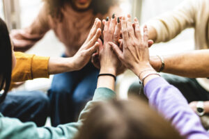 Gruppo di persone che uniscono le mani per simboleggiare collaborazione, inclusione e lavoro di squadra